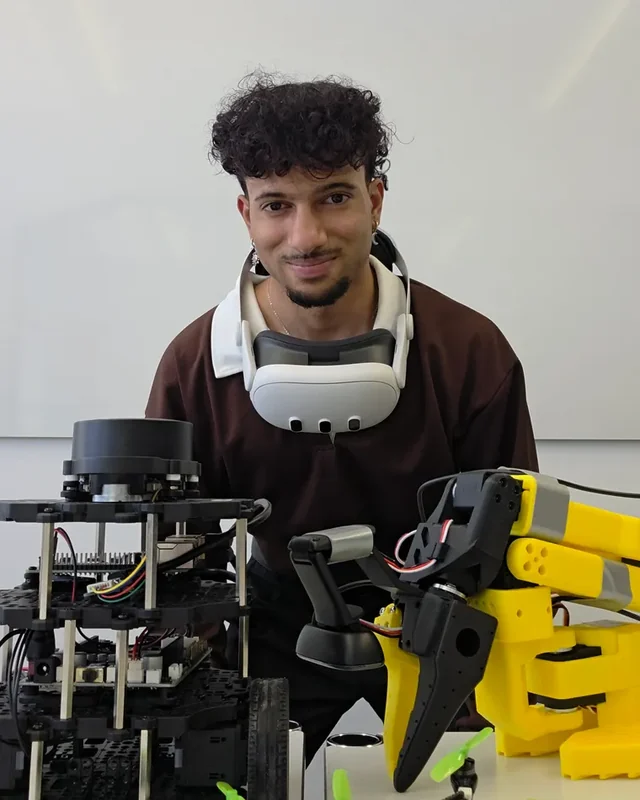 Prakash Aryan with a rover, a robot arm and small drones in the lab